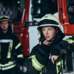 selective focus of female firefighter talking on portable radio